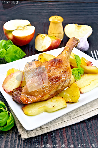 Image of Duck leg with apple and potatoes on dark board