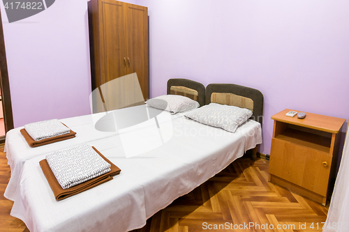 Image of The interior of a small room with a double bed, a bedside table and wardrobe