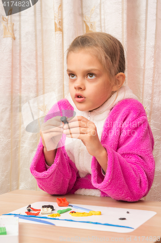 Image of Seven-year girl looked up thoughtfully engaged in modeling of plasticine