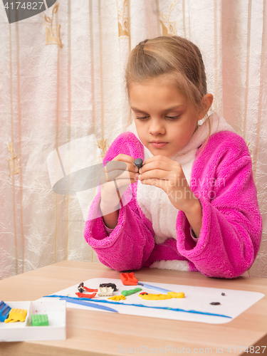 Image of Seven-year girl with enthusiasm podklku sculpts from clay