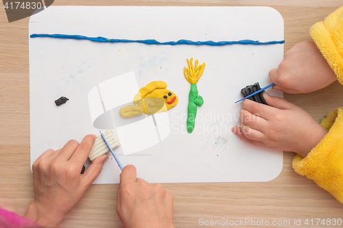 Image of Page Online Two children are molded from clay on board fish and underwater flower in the sea, the top view