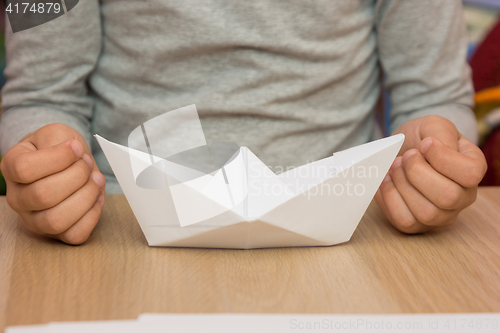 Image of On the table in front of the girl is a paper boat