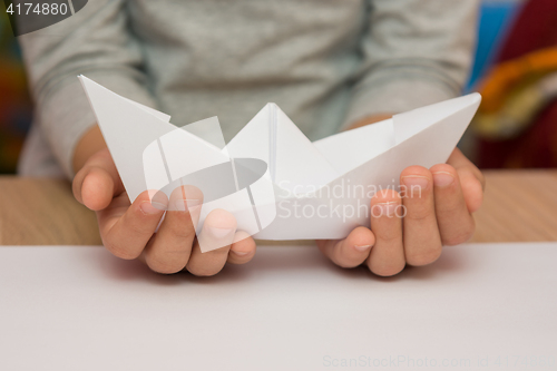 Image of A child holding a white boat made of paper