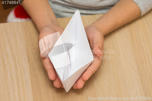 Image of The child holds in his hands a paper boat