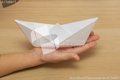Image of On the hand of the child is a paper boat on the desktop background