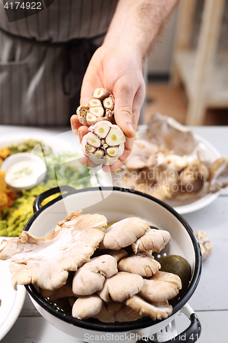 Image of A chef holding a head of fresh garlic. 