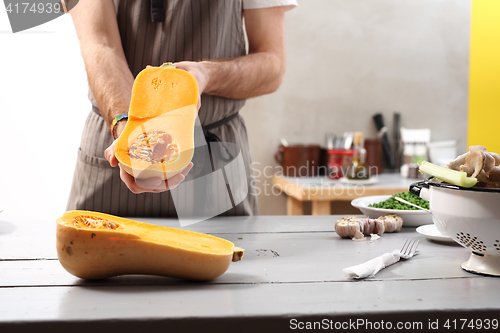 Image of The cook holds in his hands half a pumpkin. 