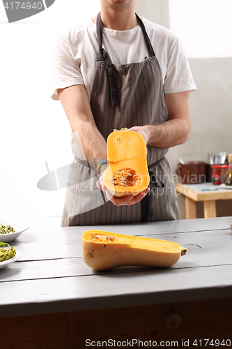 Image of The cook holds in his hands half a pumpkin. 