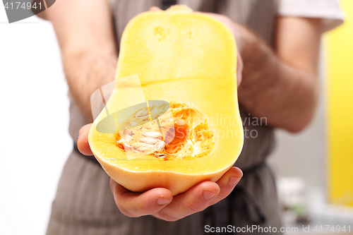 Image of Butternut squash in a vegan. The cook holds in his hands half a pumpkin. 