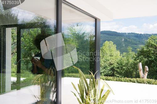 Image of African American woman drinking coffee looking out the window