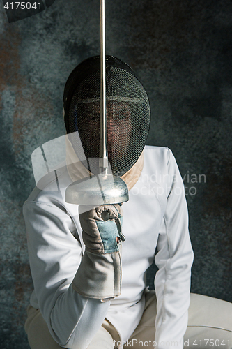 Image of The man wearing fencing suit with sword against gray