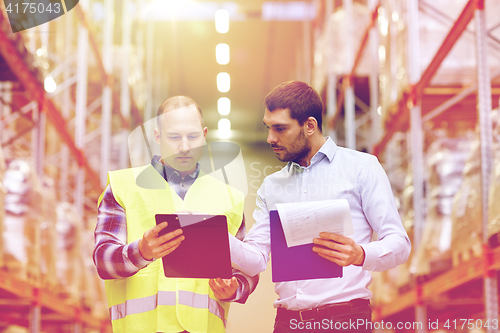 Image of worker and businessmen with clipboard at warehouse