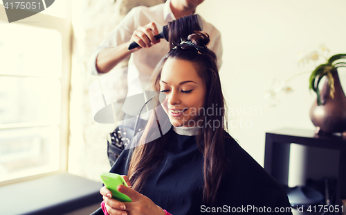 Image of happy woman with stylist making hairdo at salon