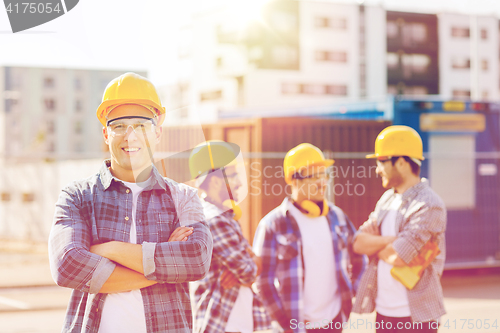 Image of group of smiling builders in hardhats outdoors