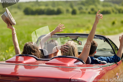 Image of happy friends driving in cabriolet car at country