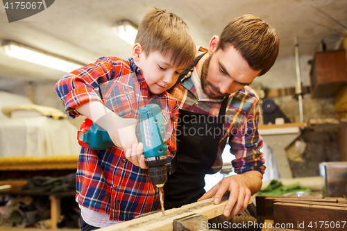 Image of father and son with drill working at workshop