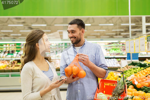 Image of happy couple buying oranges at grocery store