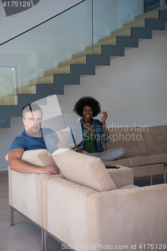 Image of multiethnic couple relaxing at  home with tablet computers