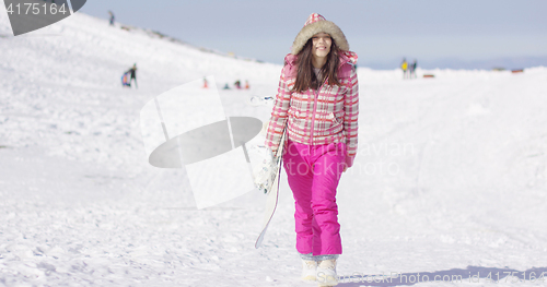 Image of Young woman walking with snowboard