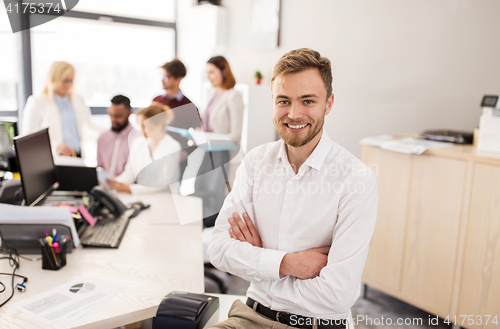 Image of happy young man over creative team in office