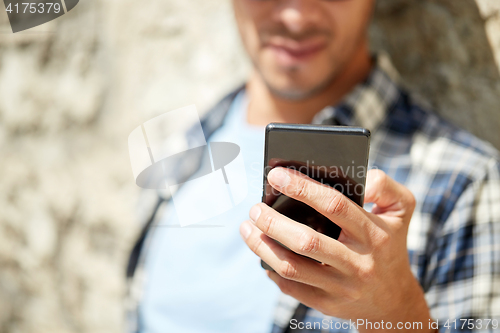 Image of man with smartphone texting message outdoors