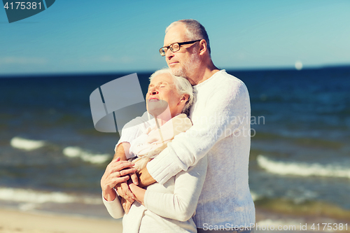 Image of happy senior couple hugging on summer beach