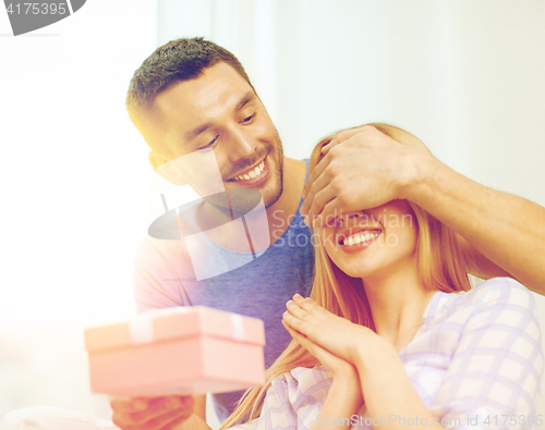 Image of smiling man surprises his girlfriend with present