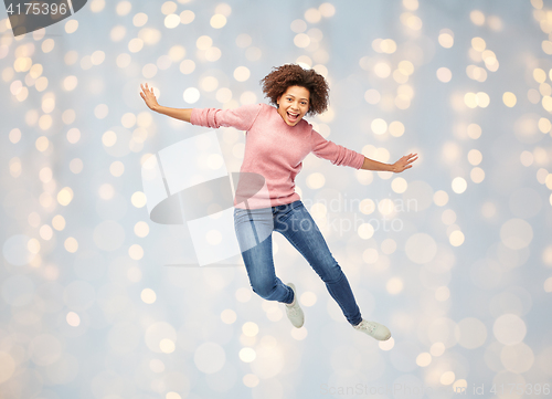 Image of happy african american woman jumping over white
