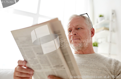 Image of close up of senior man reading newspaper at home