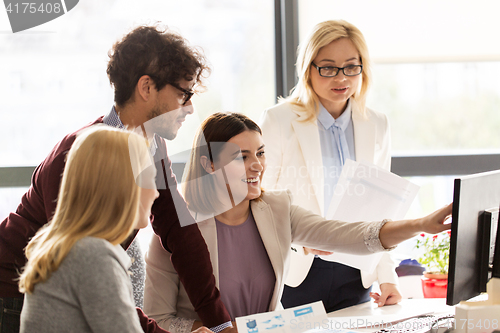 Image of happy creative team with computer in office