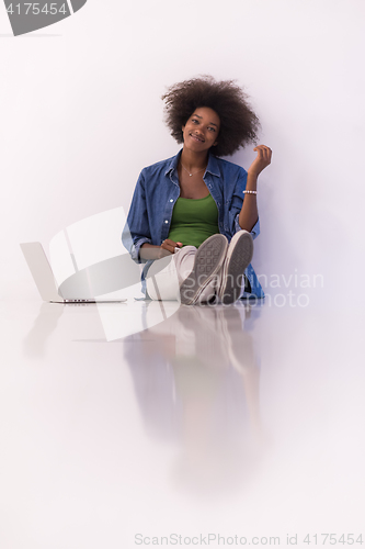 Image of african american woman sitting on floor with laptop