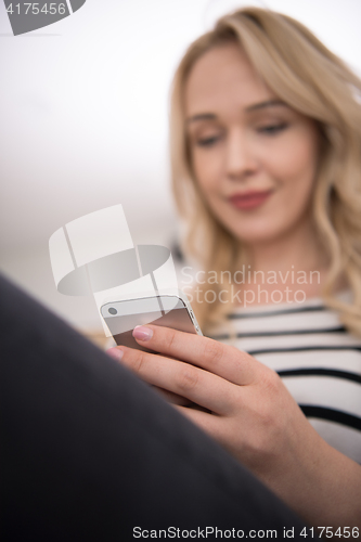 Image of woman sitting on sofa with mobile phone