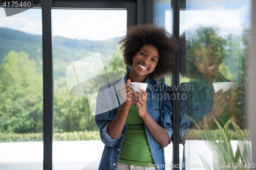 Image of African American woman drinking coffee looking out the window