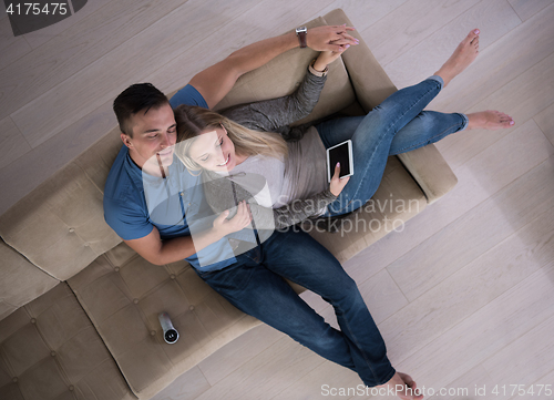 Image of youg couple in living room with tablet top view