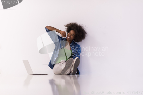 Image of african american woman sitting on floor with laptop