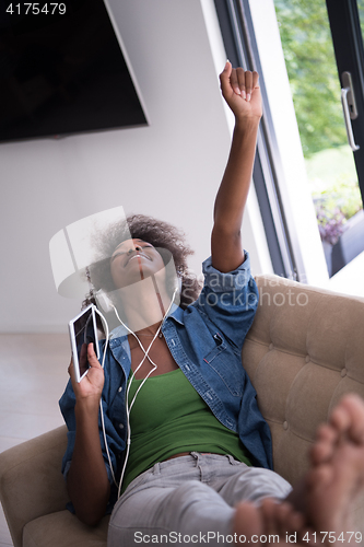 Image of African american woman at home in chair with tablet and head pho