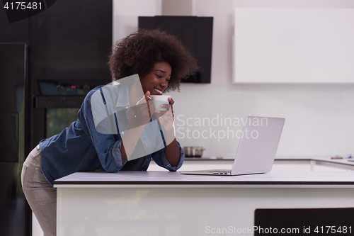 Image of smiling black woman in modern kitchen