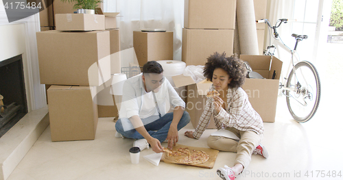 Image of Hungry young couple eating a pizza on the floor