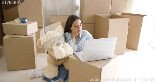 Image of Young woman moving house with her teddy bear