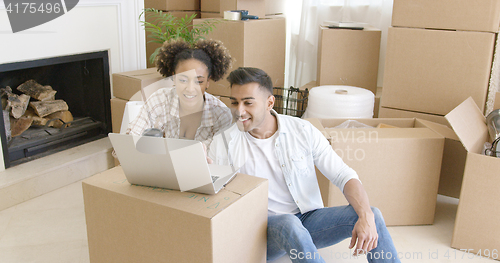 Image of Happy couple using laptop in their new apartment