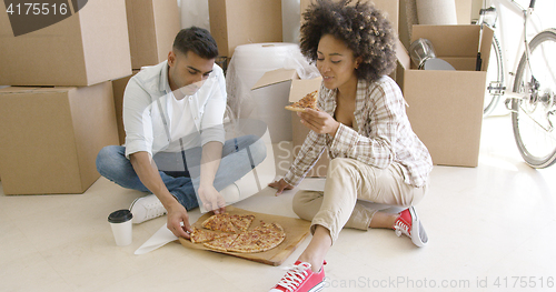 Image of Young African American couple tucking into a pizza