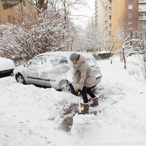 Image of Independent woman shoveling snow in winter.