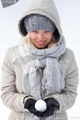 Image of Girl holding snowball in cold winter time.