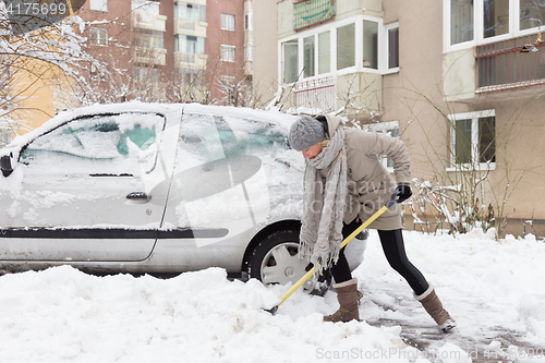 Image of Independent woman shoveling snow in winter.