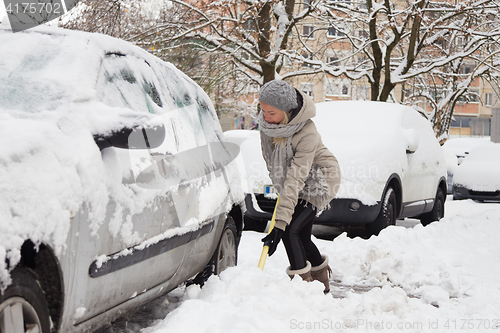 Image of Independent woman shoveling snow in winter.