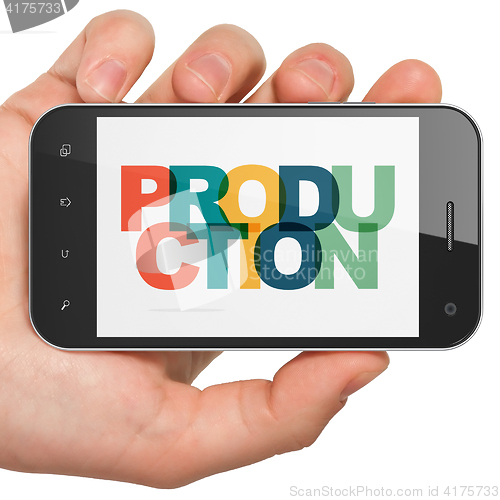 Image of Business concept: Hand Holding Smartphone with Production on  display