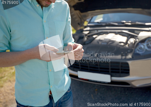 Image of close up of man with smartphone and broken car