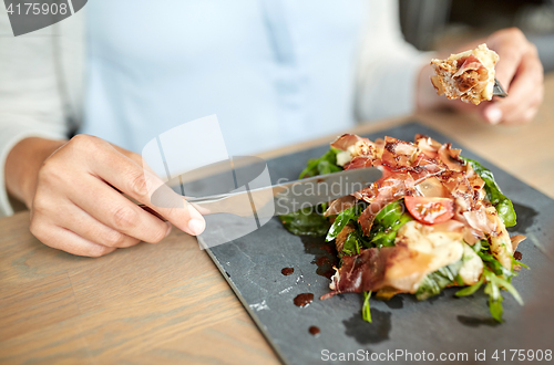 Image of woman eating prosciutto ham salad at restaurant