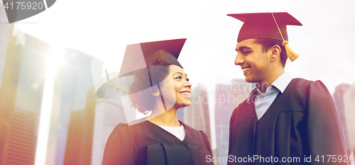 Image of happy students or bachelors in mortar boards