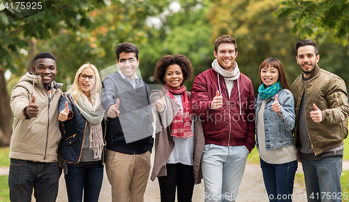 Image of happy friends showing thumbs up at autumn park